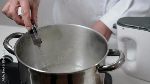 Wallpaper Mural A girl baker, in uniform, measures the temperature with a thermometer in syrup for baking cakes and desserts for the holidays. Torontodigital.ca