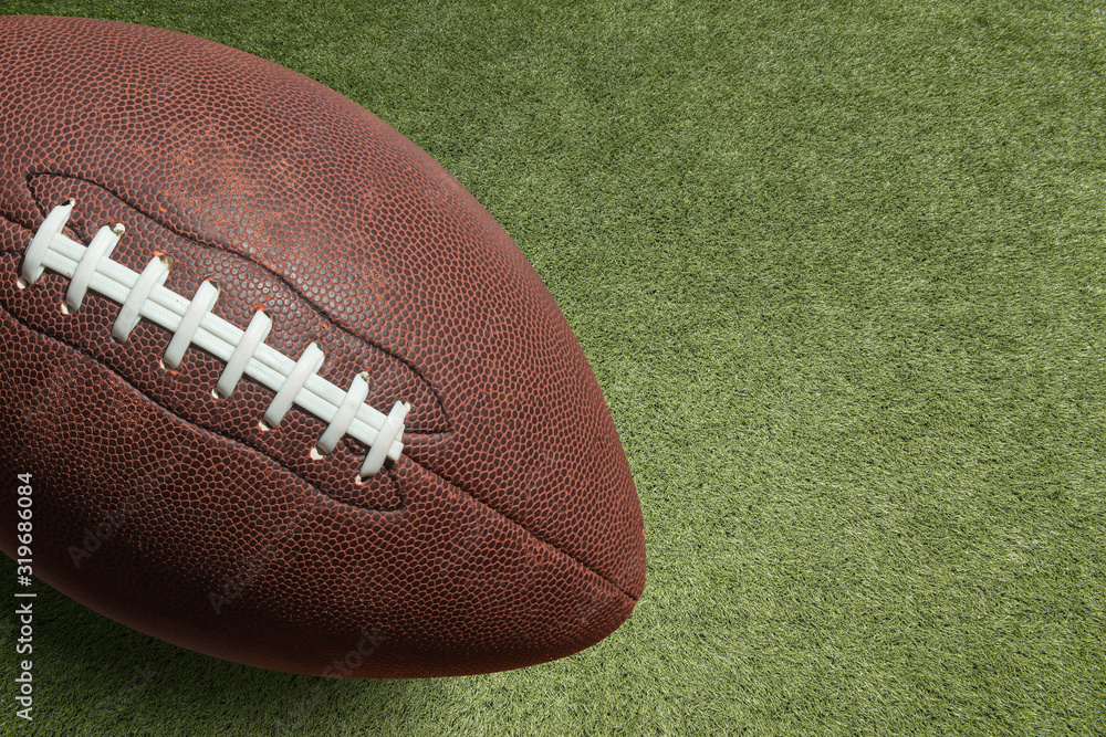 Obraz premium photo american football ball on grass stadium background.