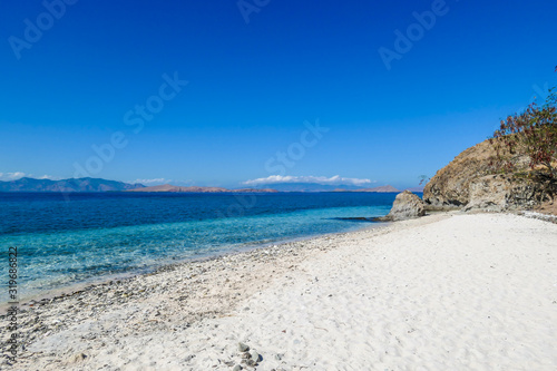 A panoramic view of idyllic white sand beach in Komodo National Park, Flores, Indonesia. Beach is gently washed by waves. Island has scarcely any plants on it. Idyllic location. Serenity and calmness
