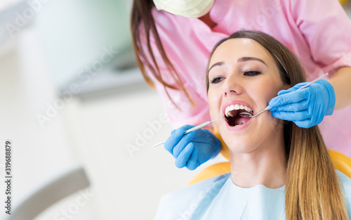 Young woman having dental check up at dentist office, showing perfect straight white teeth.