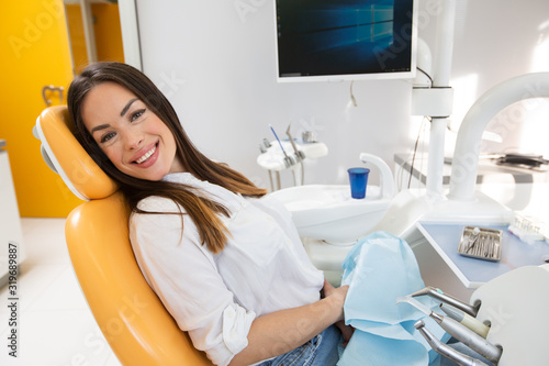 Beautiful young woman sitting on chair in dental office waiting for dental exam