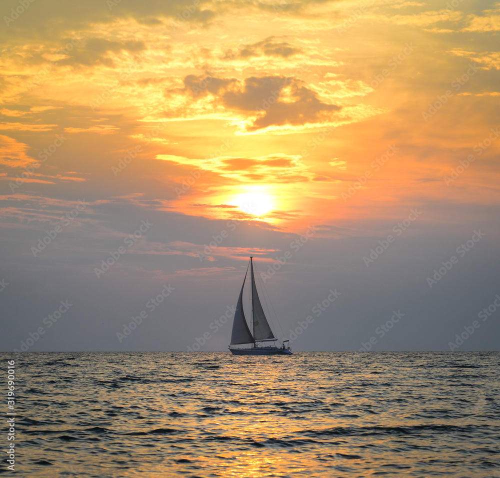 Small yacht in the sea at sunset
