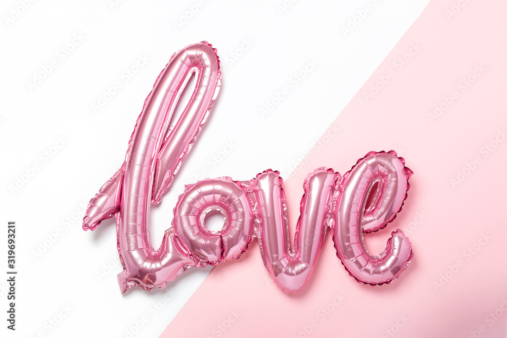 Pink balloons in the form of word Love on pink and white background. Valentines day celebration.