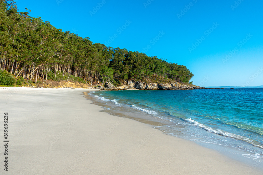 Playa virgen nudista de Figueiras sin gente cielo azul claro y bosque detrás