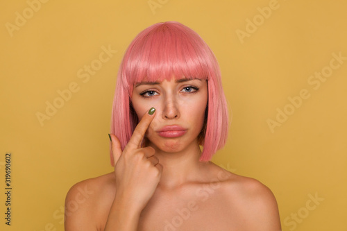 Foto Unhappy young attractive pink haired female with bob hairstyle pouting her lips