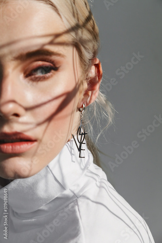 Fashion beauty portrait of young beautiful woman with shadows. Focus on the earring