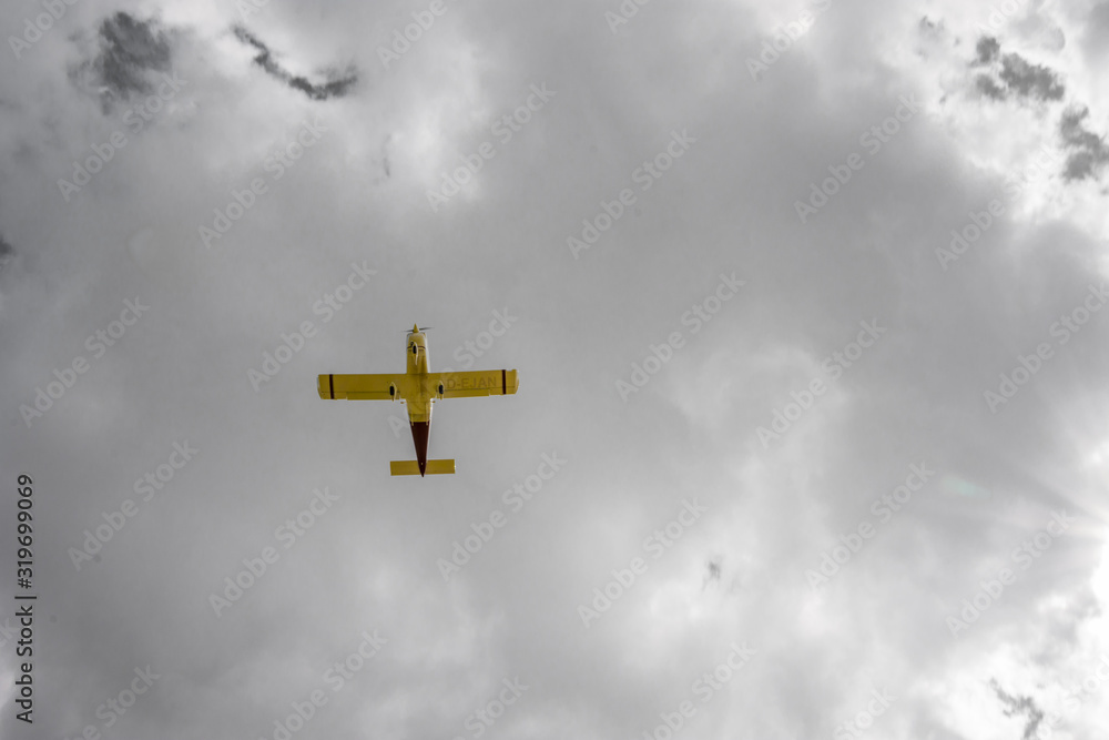 yellow airplane flying over blue sky with white clouds