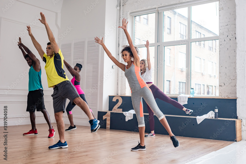 Fototapeta premium Multiethnic umba dancers with hands in air practicing in dance studio