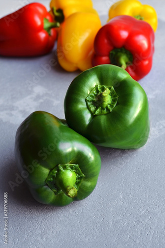 Two green fresh bell pepper with multi-colored sweet peppers. Green, red and yellow vegetables. Healthy food concept