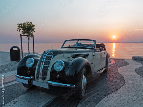 Vintage car near lake at sunset