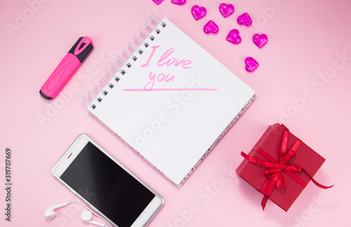 Top view image of an empty laptop, smartphone on a pink background. The concept of love with the desktop heart, Valentine's Day.
