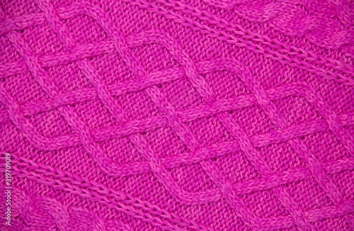 Pink wool yarn of knitted texture. Hand knitting. Close up. Pink background.