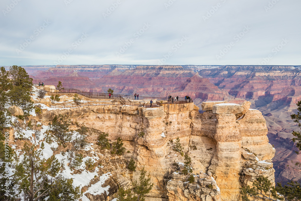 Tourists enjoying a panoramic view of the Grand Canyon along the south rim from the Mather Point on a winter day with snow