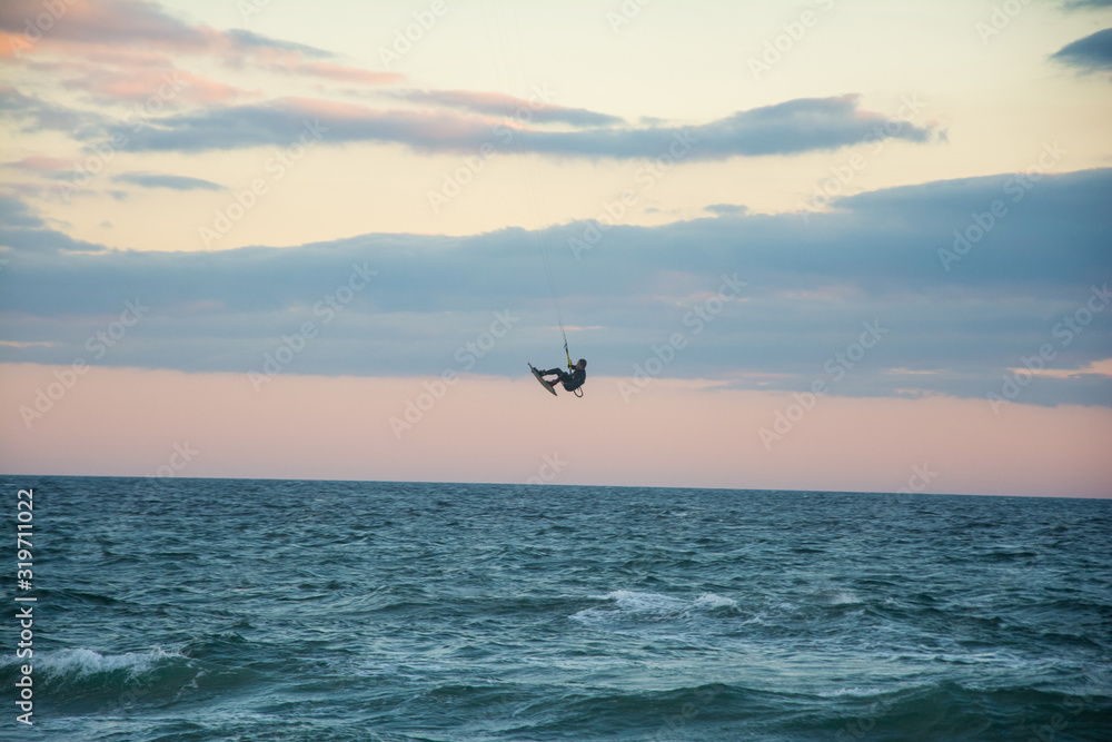 Fototapeta premium a man practicing kite surf in marbella coast, jumping and doing a trick in mid air.