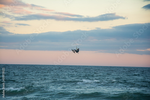 a man practicing kite surf in marbella coast, jumping and doing a trick in mid air.