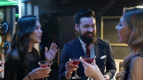 Casino: a bearded man communicates with preatty girls and they smile and laugh. Аlcoholic red champagne in the hands photo