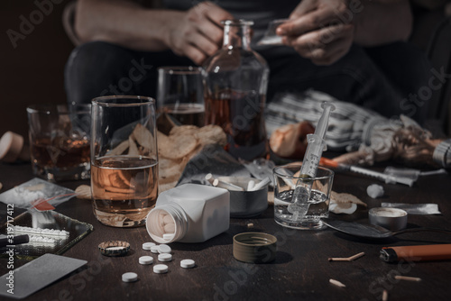 Various drugs, alcohol and cigarettes are on the wooden table. Substances that cause drug and alcohol dependence. Low key.