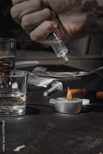 Various drugs, alcohol and cigarettes are on the wooden table. Substances that cause drug and alcohol dependence. Low key.