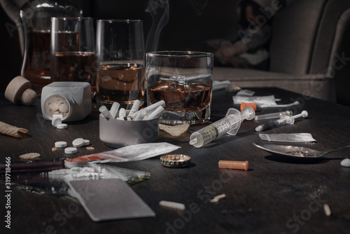 Various drugs, alcohol and cigarettes are on the wooden table. Substances that cause drug and alcohol dependence. Low key.