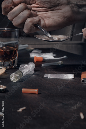 Various drugs, alcohol and cigarettes are on the wooden table. Substances that cause drug and alcohol dependence. Low key. © Александр Кузьмин