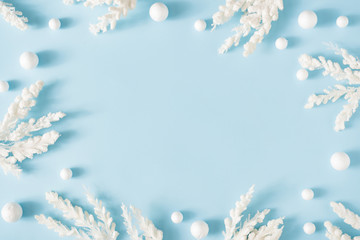 Creative winter nature layout made with snowy branches against pastel blue background. Minimal Christmas background flat lay.