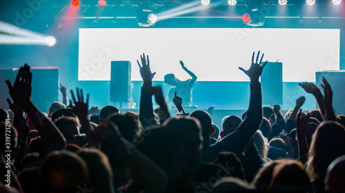 DJ performing for a crowd of party people with their hands in the air