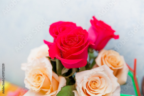 Romantic bouquet of red and creme beige roses as gift to st. Valentine holiday on colorful table and gray background