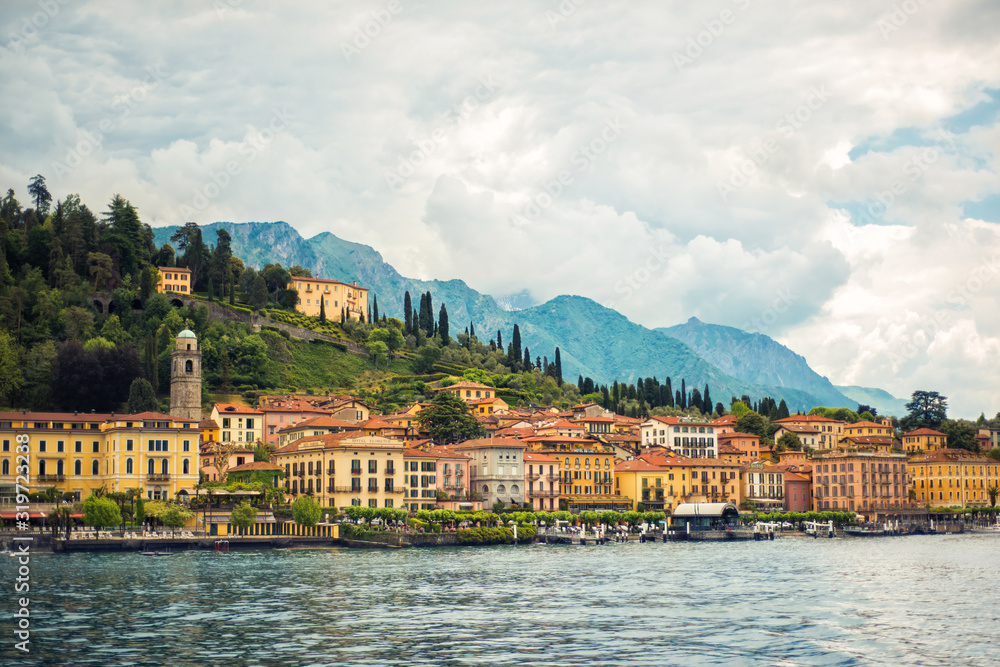 Amazing view of Como Lake and Bellagio, panorama of lake with small town and Alps mountains on background in cloudy day. Vacation on Como, Lombardy, Italy. Popular tourist destination. Italian city.