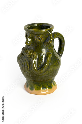 A green glazed medieval drinking jug with a face.
