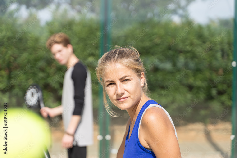 Girl with a paddle racket in front of a young boy on a paddle court Girl with a paddle racket in front of a young boy on a paddle court