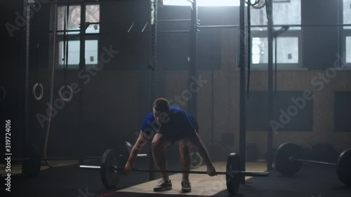 Strong man doing barbell snatch exercise at the gym in slow motion