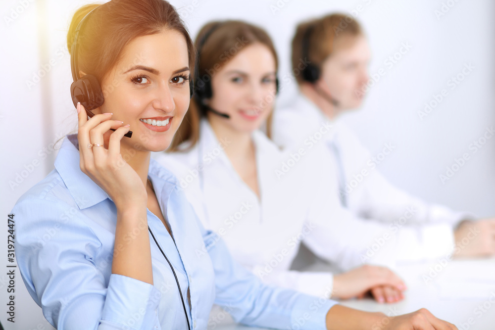 Call center. Focus on beautiful business woman using headset in sunny office Call center. Focus on beautiful business woman using headset in sunny office