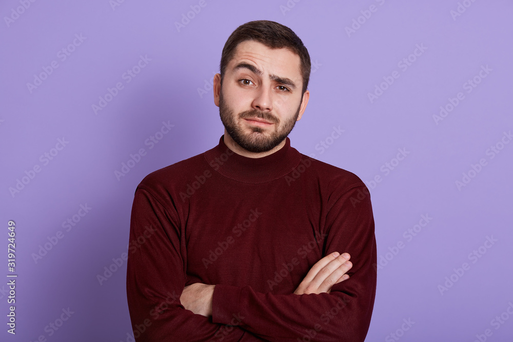 Indoor portrait of surprised impressed handsome man having folded arms, raising one eyebrow, having bewildered facial expression, looking directly at camera, being emotional. People concept. Indoor portrait of surprised impressed handsome man having folded arms, raising one eyebrow, having bewildered facial expression, looking directly at camera, being emotional. People concept.