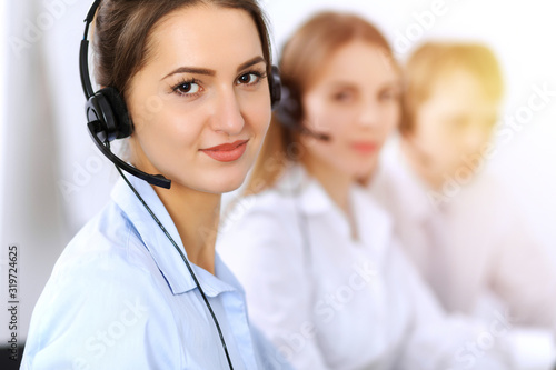 Call center. Focus on beautiful business woman using headset in sunny office