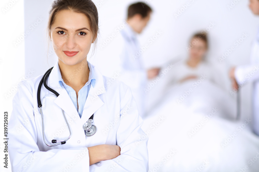 Female doctor smiling on the background with patient in the bed and two doctors Female doctor smiling on the background with patient in the bed and two doctors