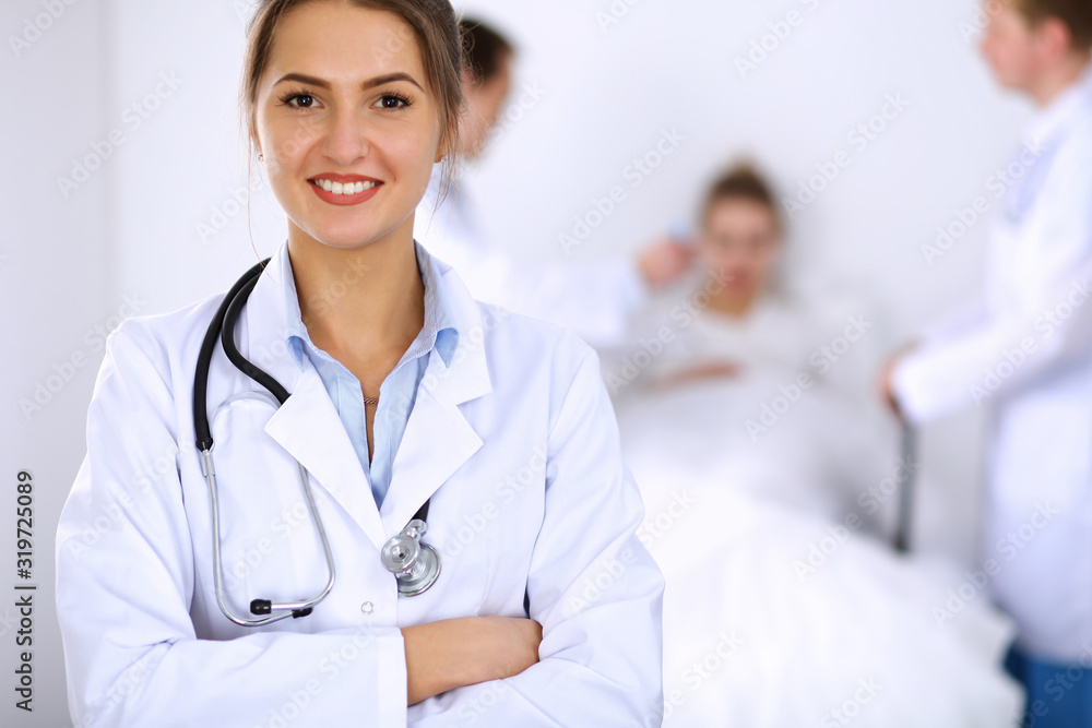 Female doctor smiling on the background with patient in the bed and two doctors Female doctor smiling on the background with patient in the bed and two doctors