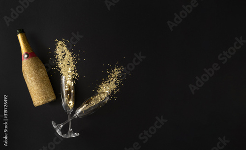 Champagne bottle ald glasses with golden glitter. Celebration party concept. Flat lay