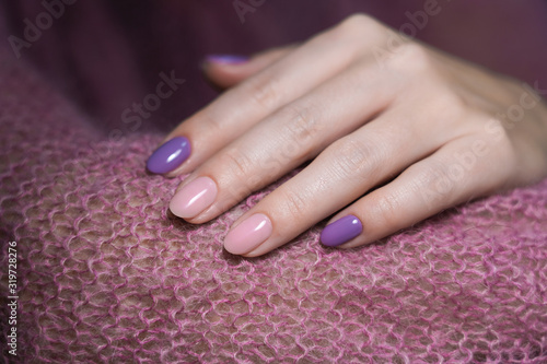 Closeup view photography of one beautiful female hand with modern trendy gel polished rounded nails painted with two colors in pink and purple. 