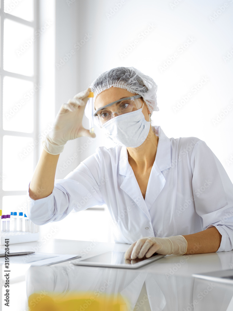 Professional female scientist in protective eyeglasses researching tube with reagents in laboratory. Concepts of medicine and research Professional female scientist in protective eyeglasses researching tube with reagents in laboratory. Concepts of medicine and research