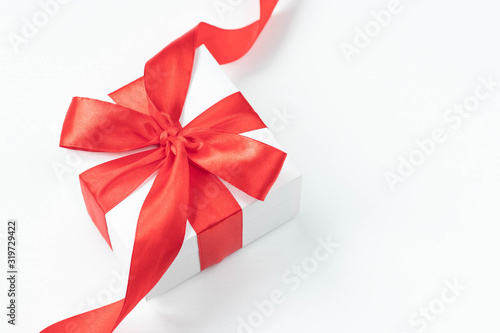 White gift box with red ribbon on white background. Top view. Holiday time at any time of the year