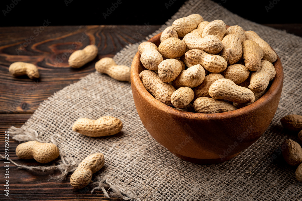 Peanut in the shell in wooden bowl on dark wooden background. Peanut in the shell in wooden bowl on dark wooden background.