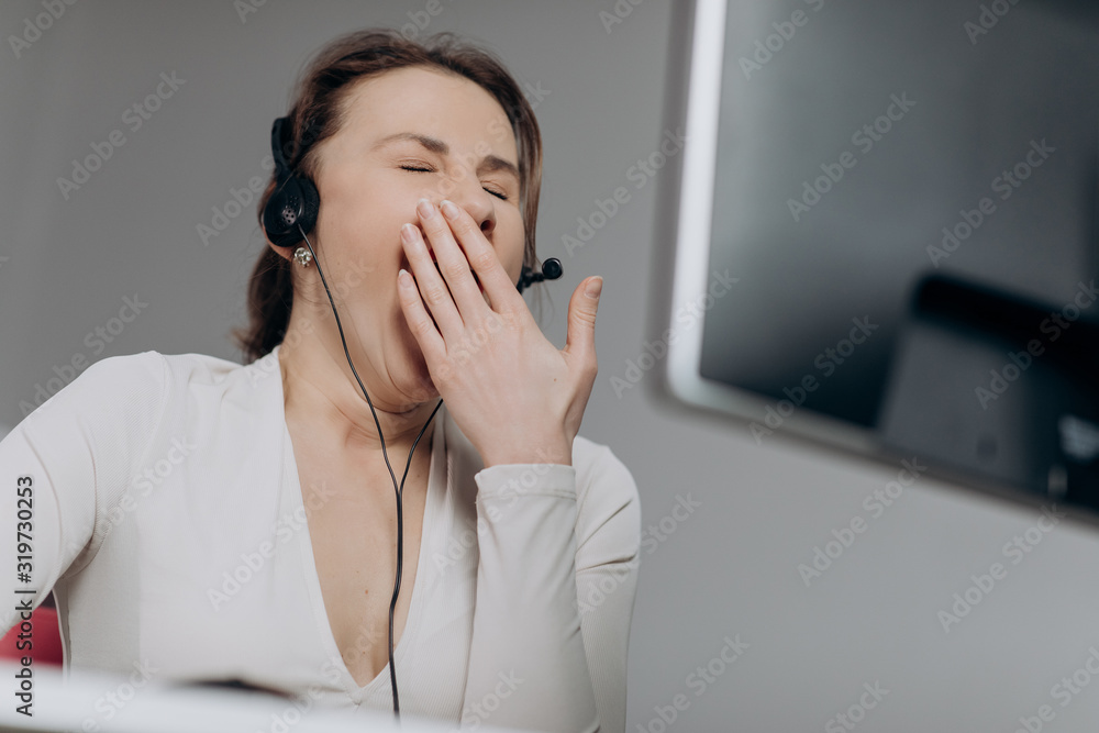 Call center operator is tired of talking to people asking stupid questions. Young customer service representative at work. Young female worker productively operating at call-centre. Call center operator is tired of talking to people asking stupid questions. Young customer service representative at work. Young female worker productively operating at call-centre.