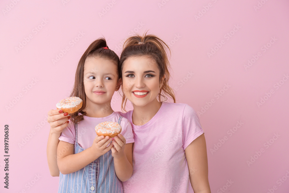 Beautiful young woman and little girl with donuts on color background Beautiful young woman and little girl with donuts on color background