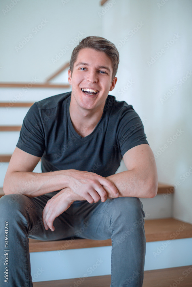 cheerful young man sitting on the steps in his house cheerful young man sitting on the steps in his house