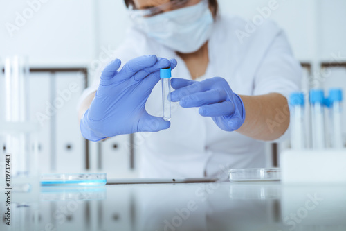 Foto Close-up of professional female scientist in protective eyeglasses making experiment with reagents in laboratory