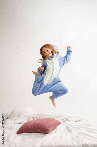 Fototapeta Naklejka Na Ścianę i Meble -  Little girl in soft warm pajama colored bright playing at home. Cute model having fun, party, laughting, playing, looks stylish and happy. Concept of childhood, leisure activity, happiness.