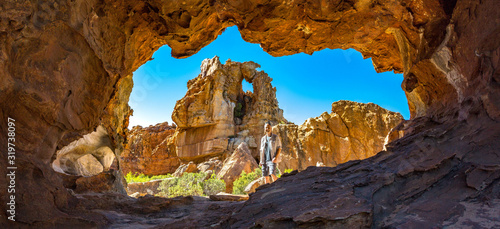 Man in front of a cave with bizarre rock formation in the background, Stadsaal, Cederberg Wilderness Area, South Africa photo