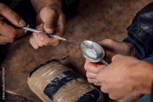 two shabby  men preparing drug injection in slums photo