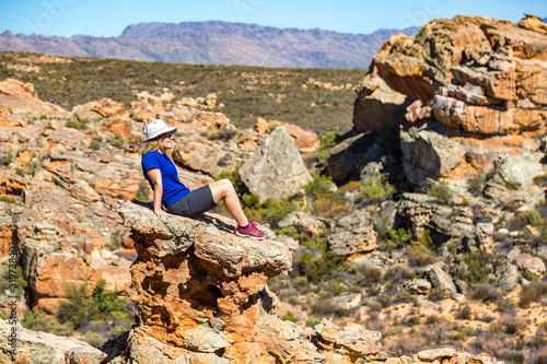 Young woman sitting on an exposed rock and enjoying the view over a bizarre landscape, Stadsaal, Cederberg Wilderness Area, South Africa photo