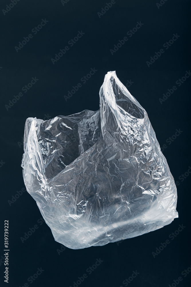 White empty plastic bag floating over wooden background. Collecting plastic waste to recycling. Concept of plastic pollution and too many plastic waste. Copy space at the top. Environmental issue